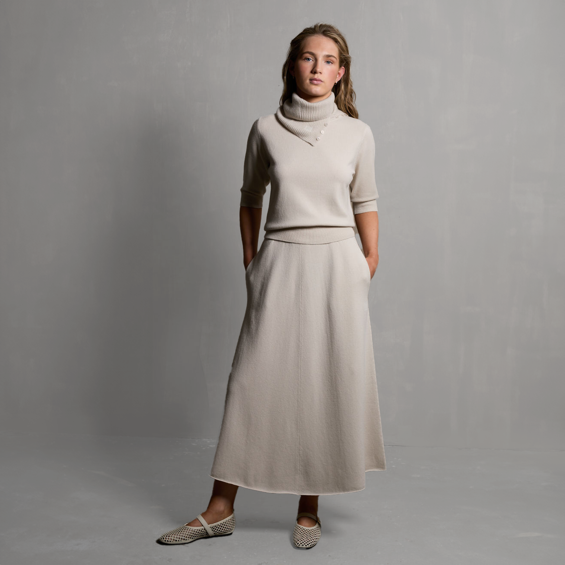 MA03 Cashmere Short Sleeve Crewneck Sweater and MA34 Cashmere A‑Line Skirt by Mawei, off-white, front view, female model.