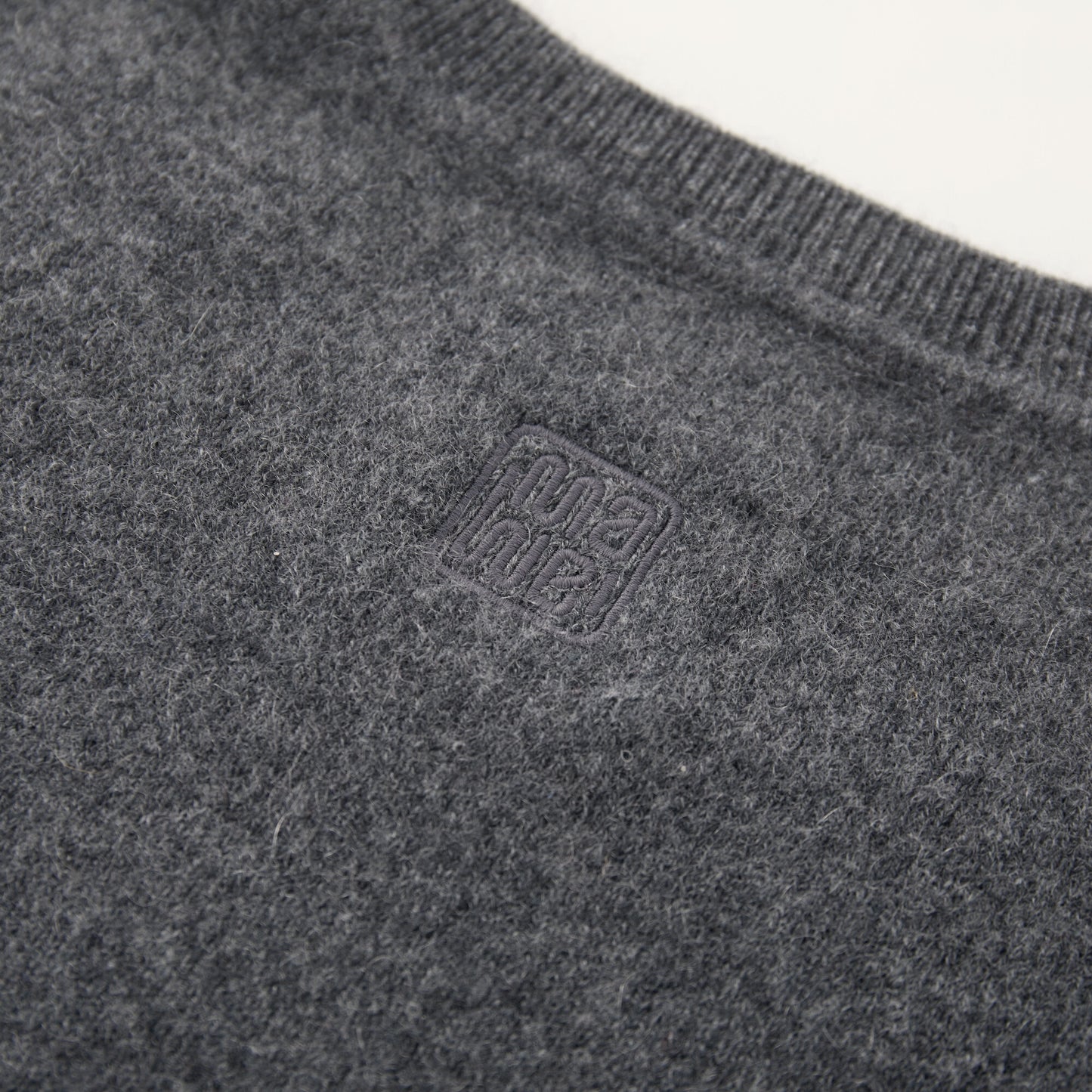 MA03 Cashmere Short Sleeve Crewneck Sweater by Mawei, grey, fabric and logo embroidery detail close-up, back view.