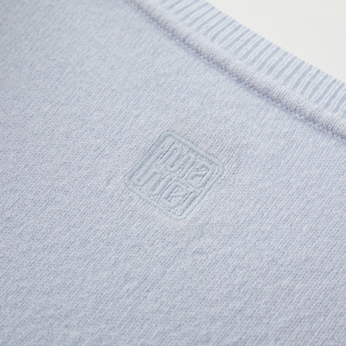 MA03 Cashmere Short Sleeve Crewneck Sweater by Mawei, blue, fabric and logo embroidery detail close-up, back view.