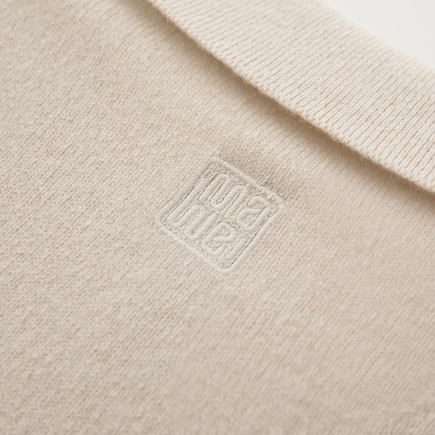 MA09 Cashmere Short Sleeve Polo Sweater by Mawei, off white, fabric and logo embroidery close up, back view.